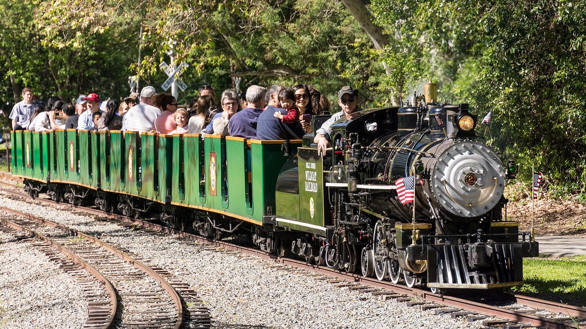 The Billy Jones Wildcat Railroad steam engine pulling open cars full of riders