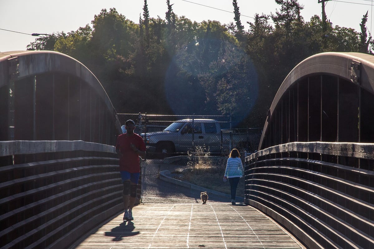 Walkers crossing a covered bridge over Los Gatos Creek