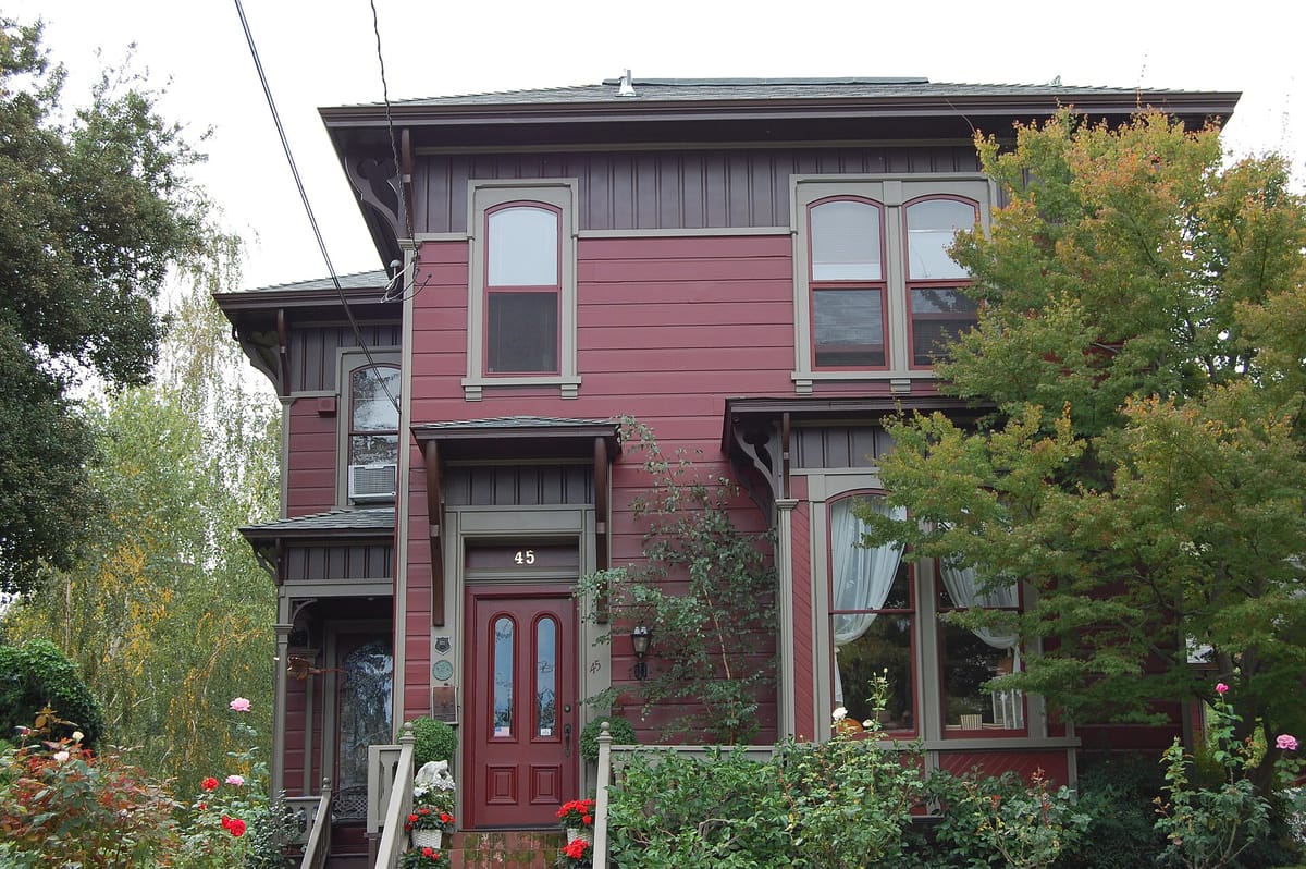 A two-story Italianate house among roses on Broadway